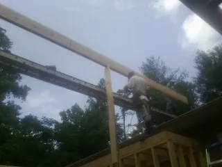 Carpenter setting a ridge beam over a new addition frame — Ice Dam Removal by Roofing Brothers in Carrier