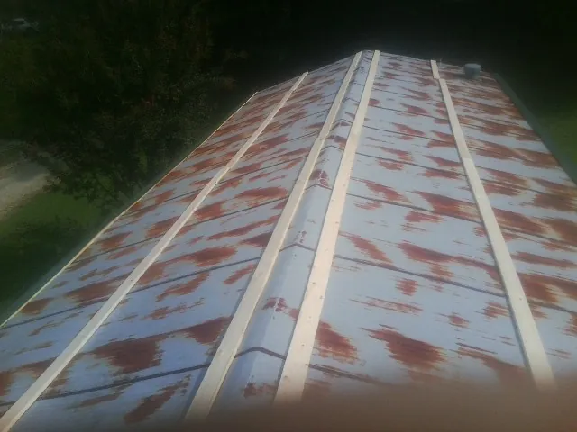 Rusted metal roof panels with new wood purlins before replacement — Storm Damage Roof Repair in Carrier by Roofing Brothers