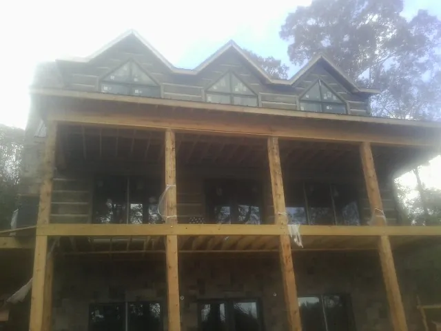 Dormers and porch framing on a large log home under construction — Roof Coating work by our crew in Carrier