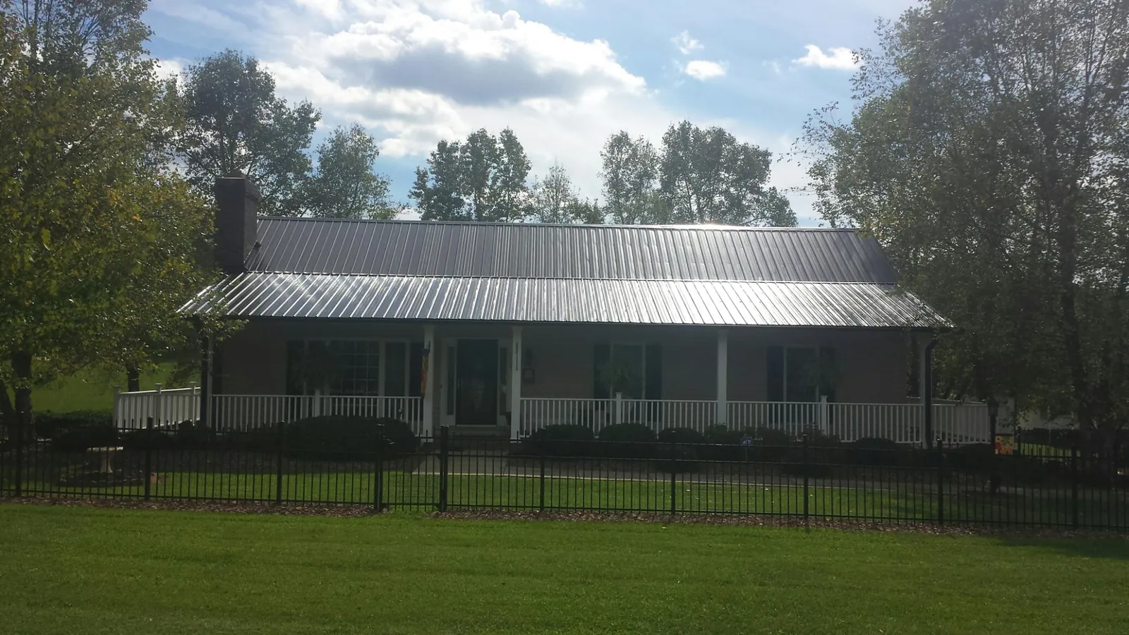 Gray metal roof on a brick ranch with a full width front porch — Gutter Guard Installation work by our crew in Carrier