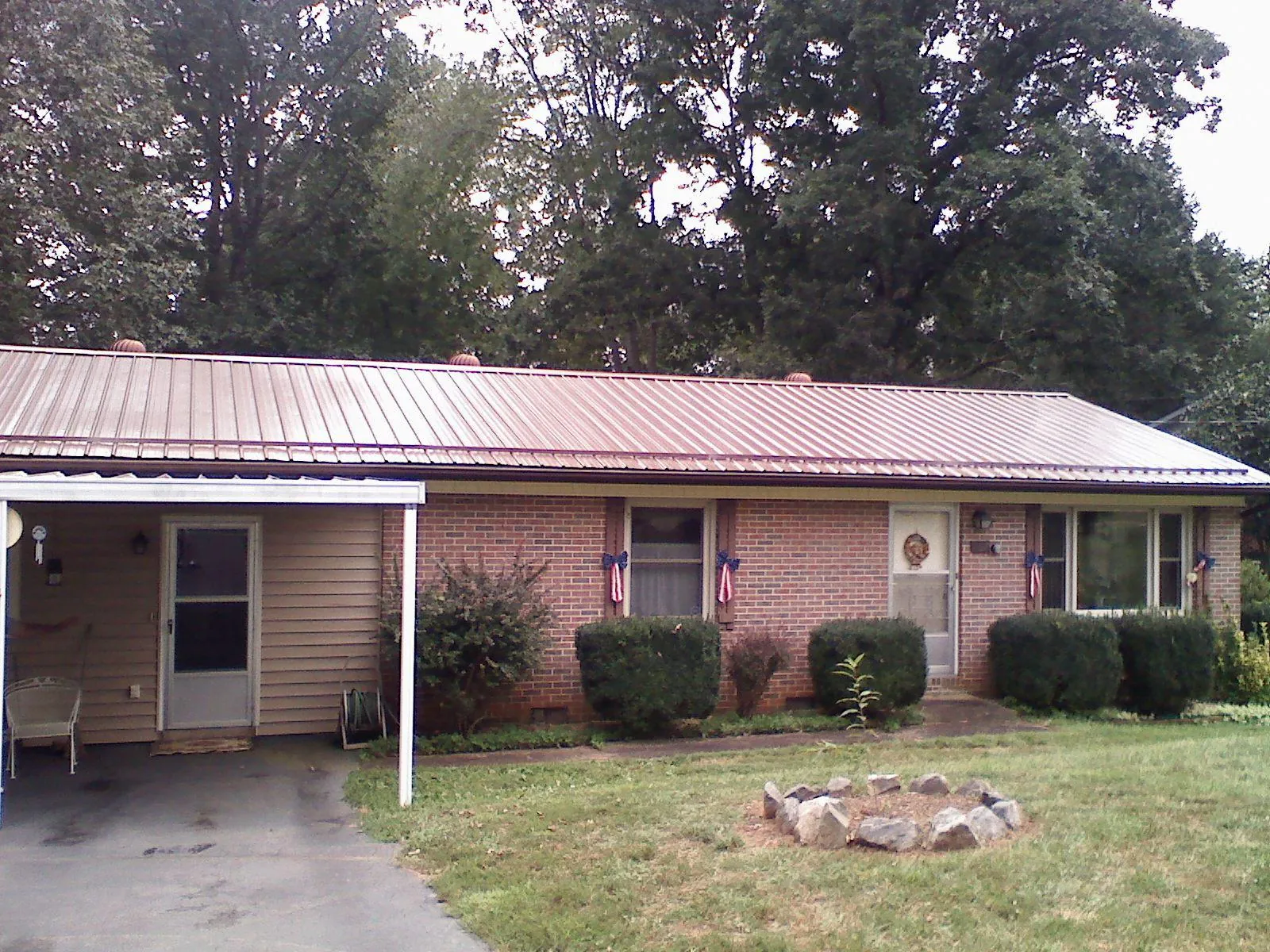 Bronze metal roof and carport on a brick ranch home — Roof Repair work by our crew in Carrier